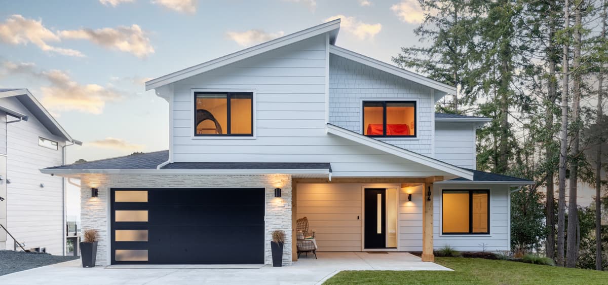 Modern Hardie siding home at twilight with warm interior glow and stone accents