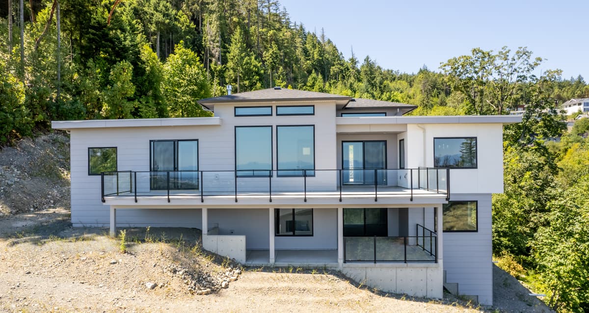 Modern white Hardie siding hillside home with glass railings
