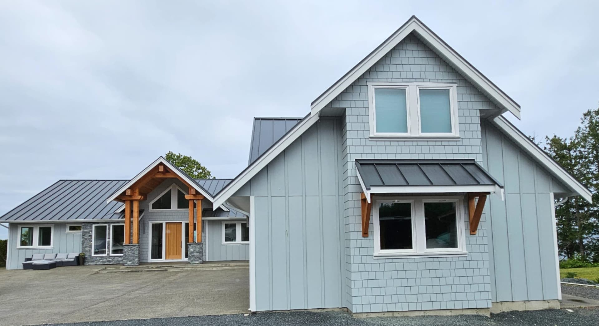 Light blue Hardie board and batten and shingle siding with a metal roof and timber entry