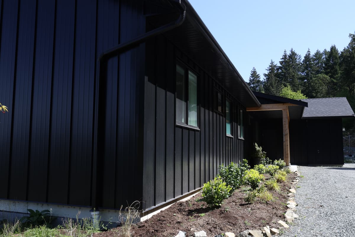 Black metal board and batten siding with landscaping